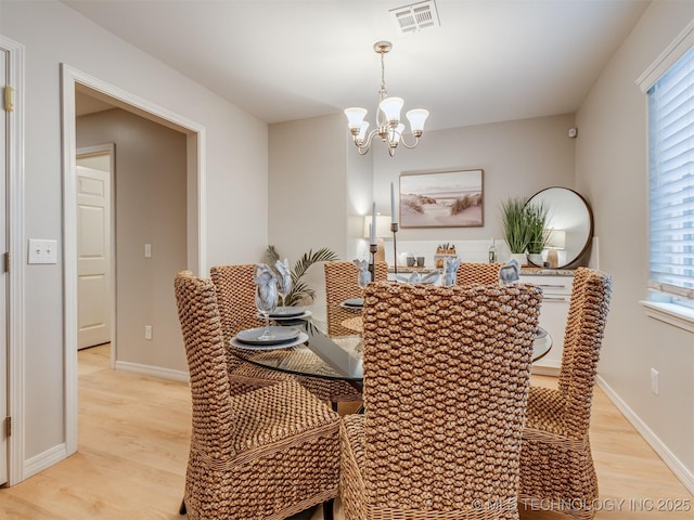 dining area with visible vents, a wealth of natural light, light wood-style flooring, and an inviting chandelier