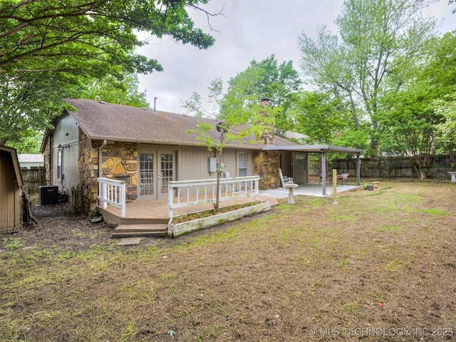 back of property featuring stone siding, a fenced backyard, a chimney, a patio area, and central air condition unit