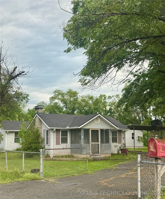 ranch-style home with roof with shingles, a fenced front yard, a chimney, and a front lawn