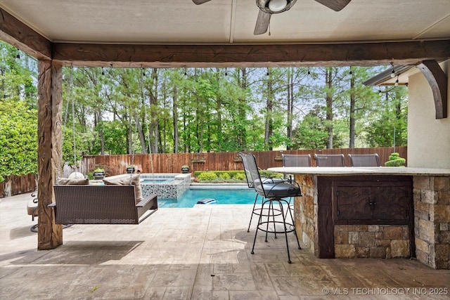exterior space featuring outdoor dry bar, a pool with connected hot tub, ceiling fan, a fenced backyard, and a patio