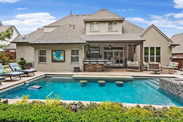 rear view of house featuring an outdoor pool, outdoor dry bar, a patio, a shingled roof, and stucco siding