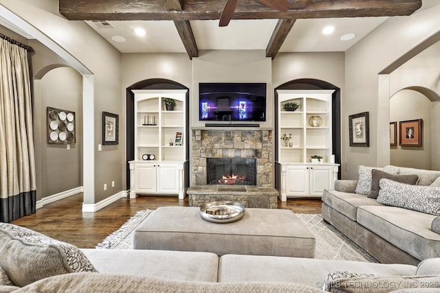living room featuring baseboards, beamed ceiling, wood finished floors, and a fireplace