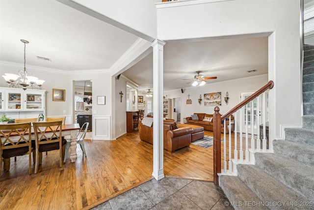 interior space with stairs, crown molding, visible vents, and ceiling fan with notable chandelier