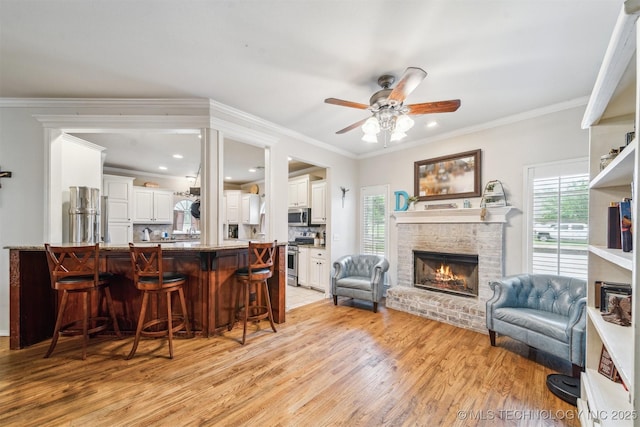 living area with plenty of natural light, light wood finished floors, a brick fireplace, and ceiling fan
