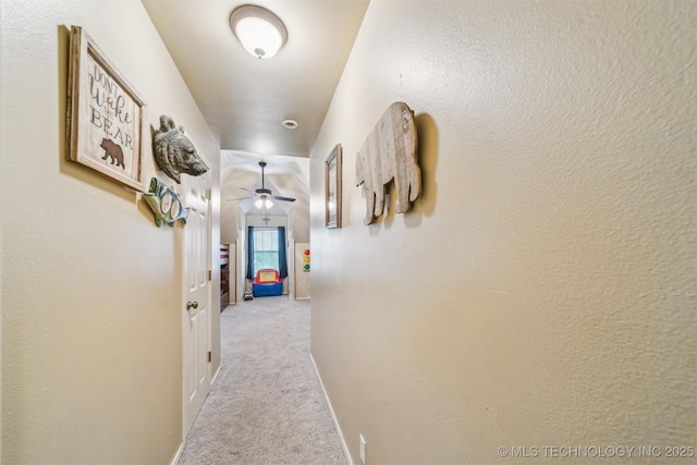 hall featuring baseboards and carpet flooring