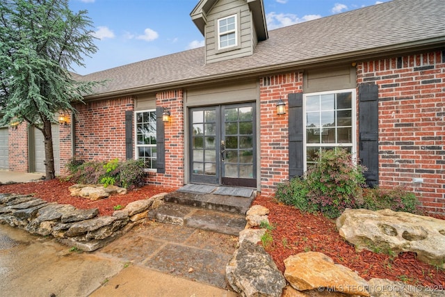 property entrance featuring brick siding, roof with shingles, and french doors