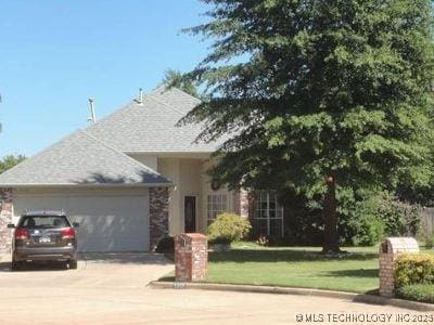 view of front of house with an attached garage, driveway, and a front lawn