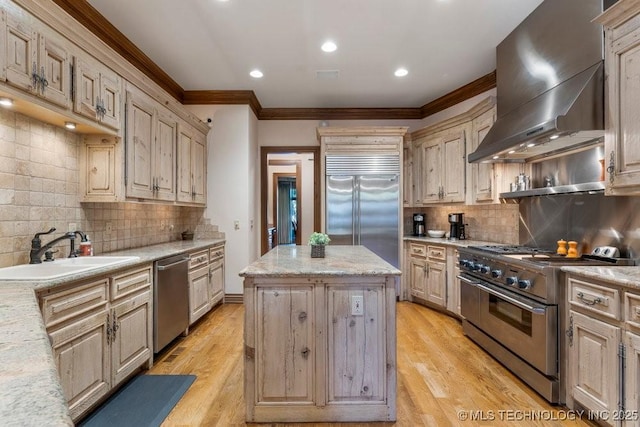 kitchen featuring crown molding, a kitchen island, wall chimney range hood, high quality appliances, and a sink