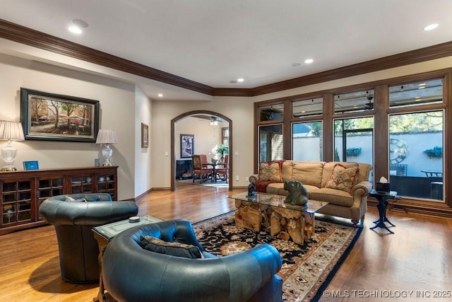 living area with crown molding, arched walkways, recessed lighting, and light wood-style floors