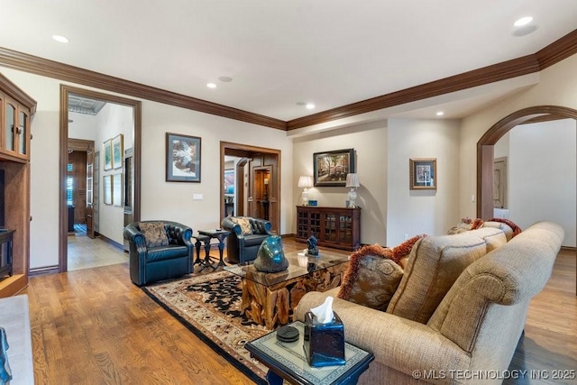 living area featuring light wood-style floors, ornamental molding, arched walkways, and recessed lighting