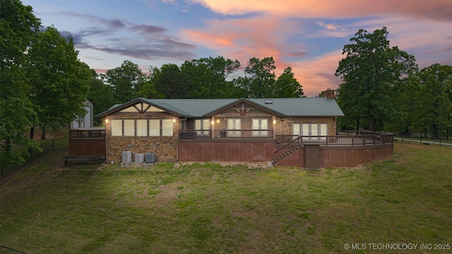 rear view of house featuring metal roof, a wooden deck, a yard, stairs, and stone siding