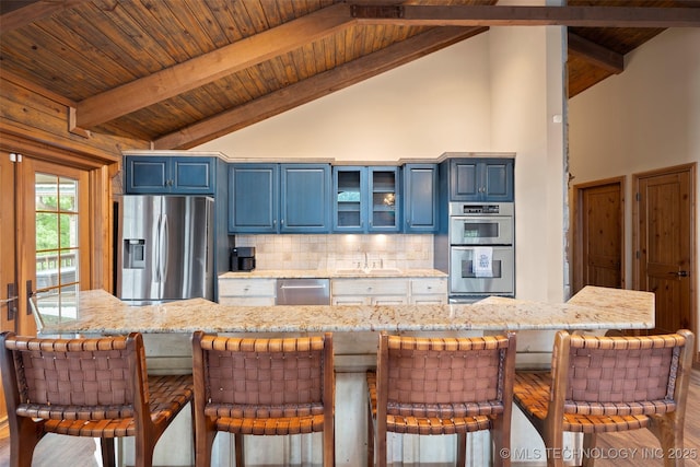 53402 E 332nd Loop, Jay, OK 74346 - kitchen featuring stainless steel appliances, blue cabinets, backsplash, a kitchen bar, and wood finished floors