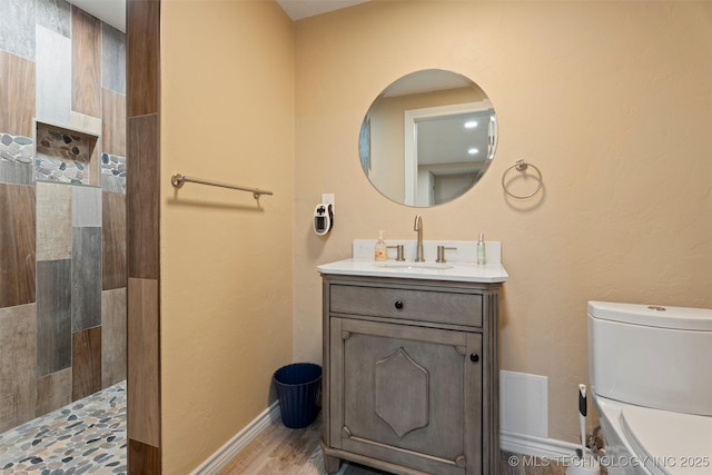 bathroom with walk in shower, vanity, toilet, baseboards, and wood finished floors
