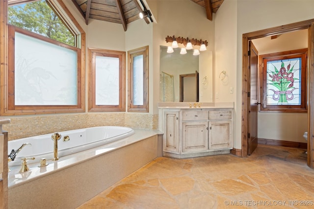 bathroom featuring vaulted ceiling with beams, stone finish flooring, a bath, and wooden ceiling