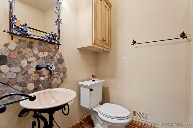 half bathroom featuring baseboards, toilet, and visible vents