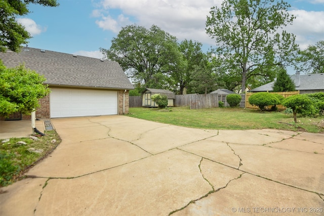 exterior space featuring a storage unit, a fenced backyard, an outbuilding, and concrete driveway