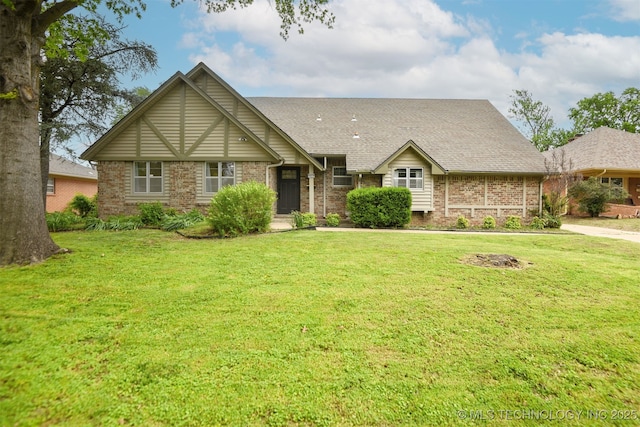 view of front of house with brick siding, roof with shingles, and a front yard