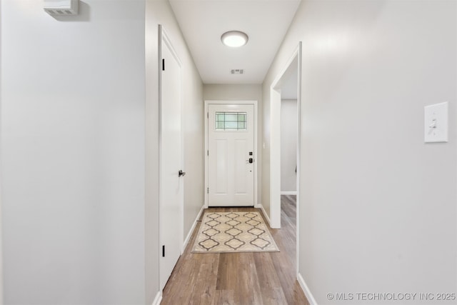 doorway featuring baseboards, light wood finished floors, and visible vents