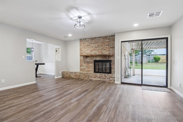 unfurnished living room with visible vents, baseboards, plenty of natural light, and wood finished floors