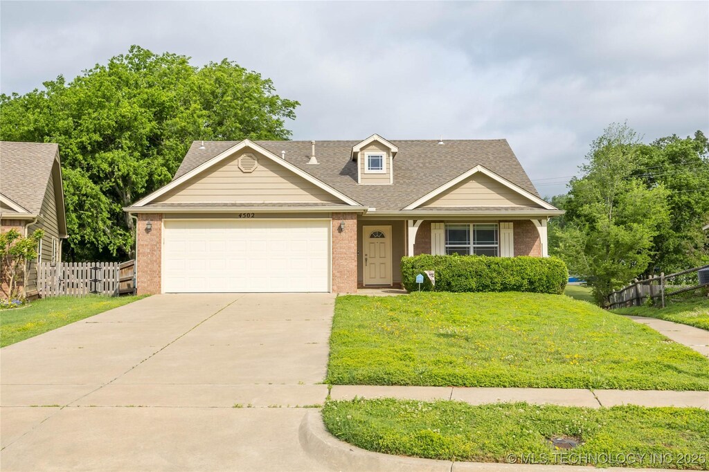 4502 Stevens Ave, Sand Springs, OK 74063 - view of front facade featuring fence, a front lawn, brick siding, a garage, and concrete driveway