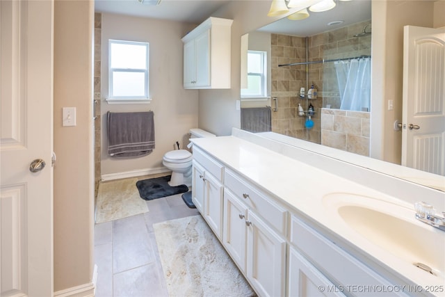 full bathroom featuring vanity, toilet, a tile shower, and plenty of natural light