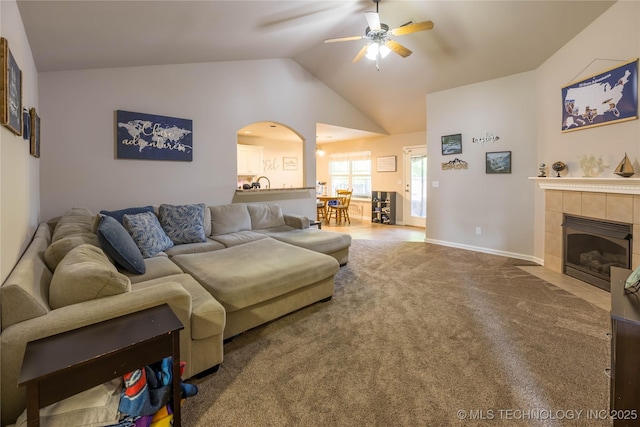 carpeted living area with a ceiling fan, arched walkways, lofted ceiling, and a fireplace