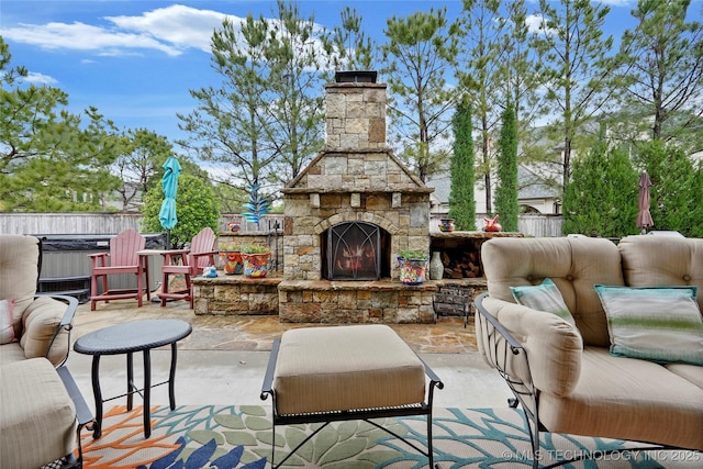 view of patio / terrace featuring an outdoor living space with a fireplace, fence, and a jacuzzi