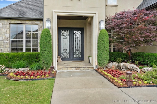 property entrance featuring roof with shingles, stucco siding, and stone siding