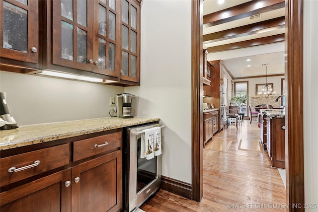 bar featuring an inviting chandelier, crown molding, light wood-type flooring, a sink, and wine cooler