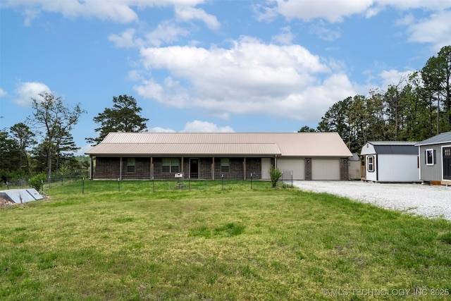 ranch-style house with an attached garage, metal roof, a front lawn, and gravel driveway