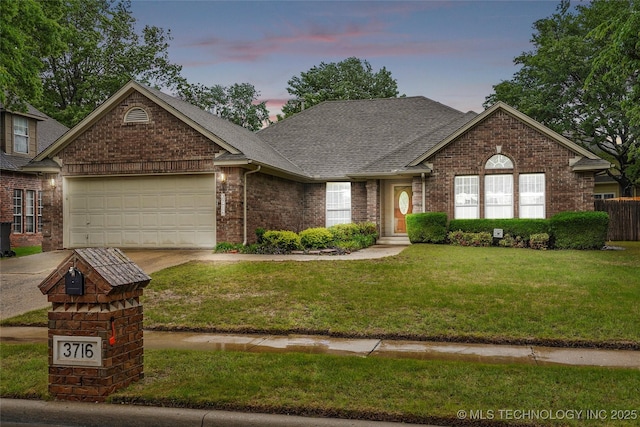 ranch-style home featuring an attached garage, concrete driveway, a front yard, and brick siding