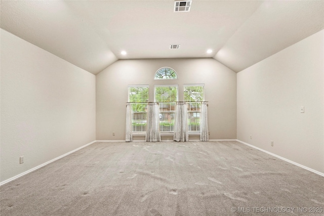 carpeted spare room featuring baseboards, lofted ceiling, and visible vents