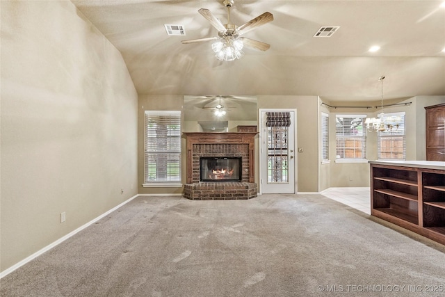 unfurnished living room with visible vents, a brick fireplace, baseboards, ceiling fan with notable chandelier, and carpet flooring