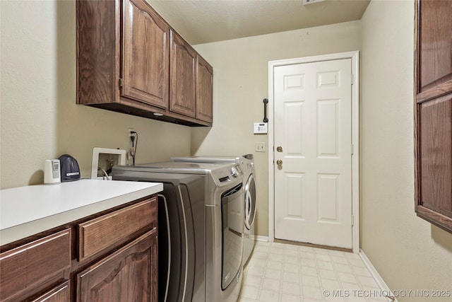 clothes washing area with cabinet space, baseboards, light floors, and washer and dryer