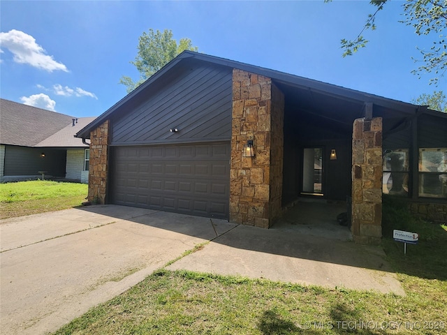 view of front facade with driveway, stone siding, and a garage