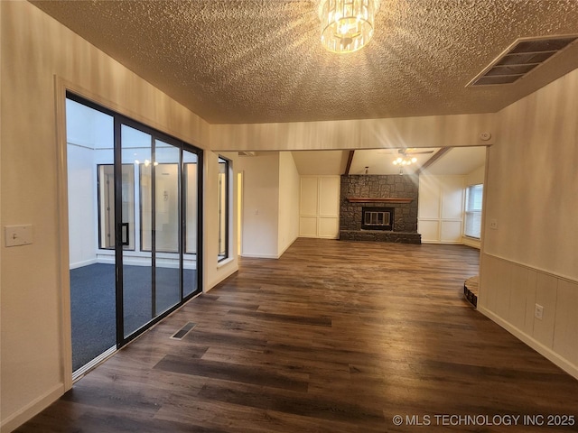 unfurnished living room featuring visible vents, a fireplace, a textured ceiling, and dark wood-type flooring