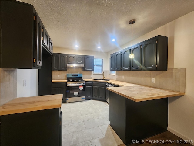 kitchen with a peninsula, wood counters, appliances with stainless steel finishes, and backsplash