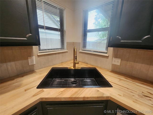 room details featuring a sink, dark cabinetry, wooden counters, and wood walls