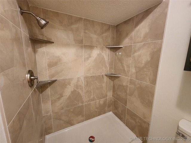 bathroom featuring tiled shower, toilet, and a textured ceiling