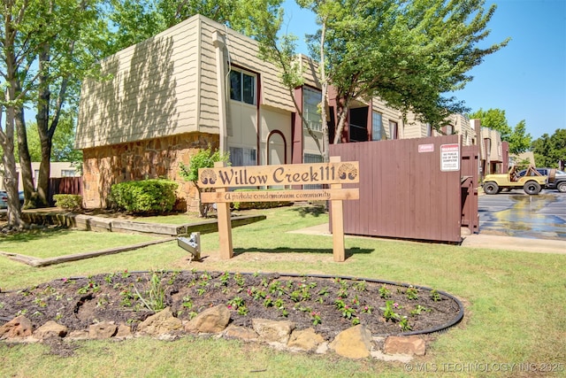 community sign with uncovered parking and a yard