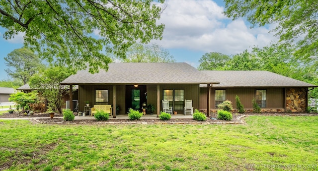 single story home with roof with shingles, a front lawn, and stone siding