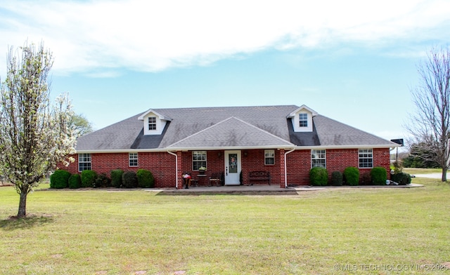 view of front facade with brick siding, a shingled roof, and a front lawn