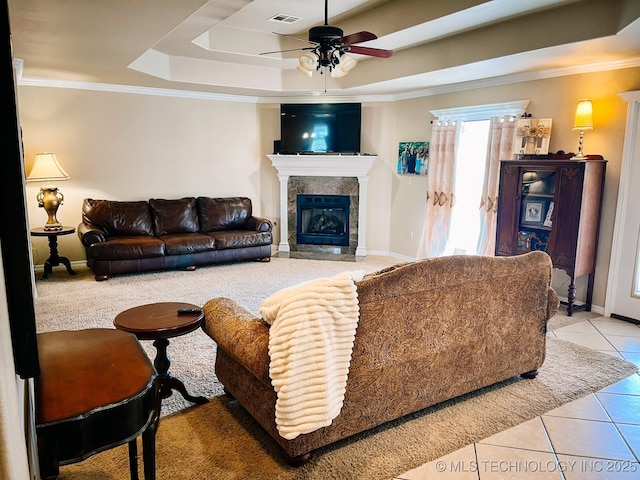living room with ceiling fan, visible vents, a tile fireplace, a raised ceiling, and tile patterned floors