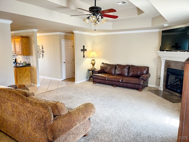 living area featuring crown molding, visible vents, baseboards, ceiling fan, and a tile fireplace