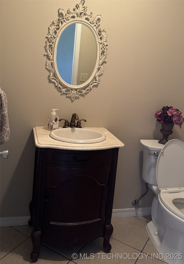 half bath with toilet, baseboards, tile patterned flooring, and vanity