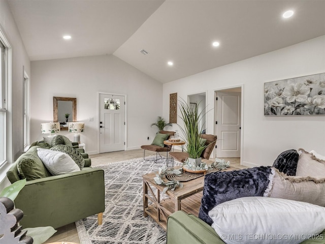 living room with visible vents, baseboards, light wood finished floors, lofted ceiling, and recessed lighting