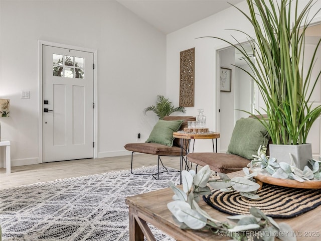entryway featuring baseboards, vaulted ceiling, and light wood-type flooring