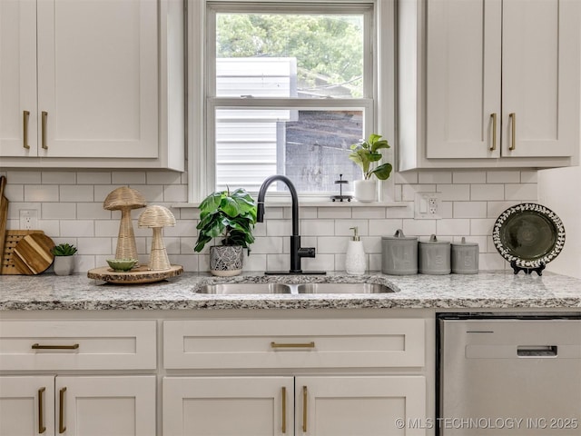 kitchen with stainless steel dishwasher, white cabinetry, a sink, and tasteful backsplash