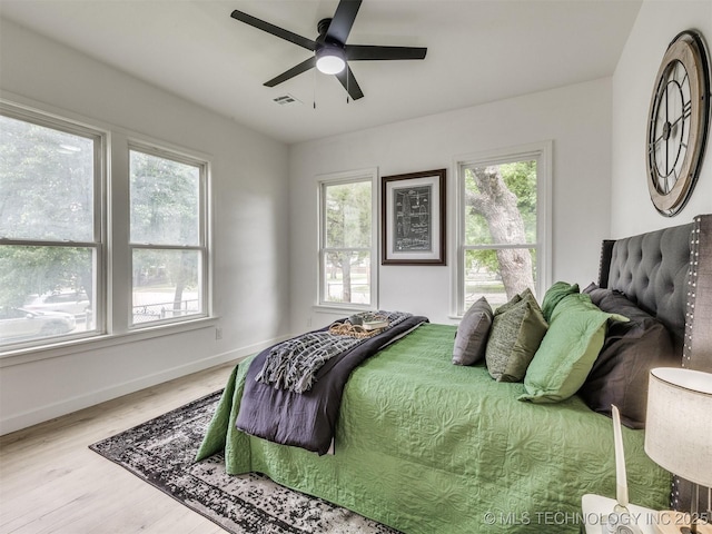 bedroom featuring visible vents, baseboards, wood finished floors, and multiple windows
