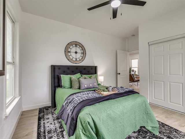 bedroom featuring ceiling fan, baseboards, and light wood-style floors